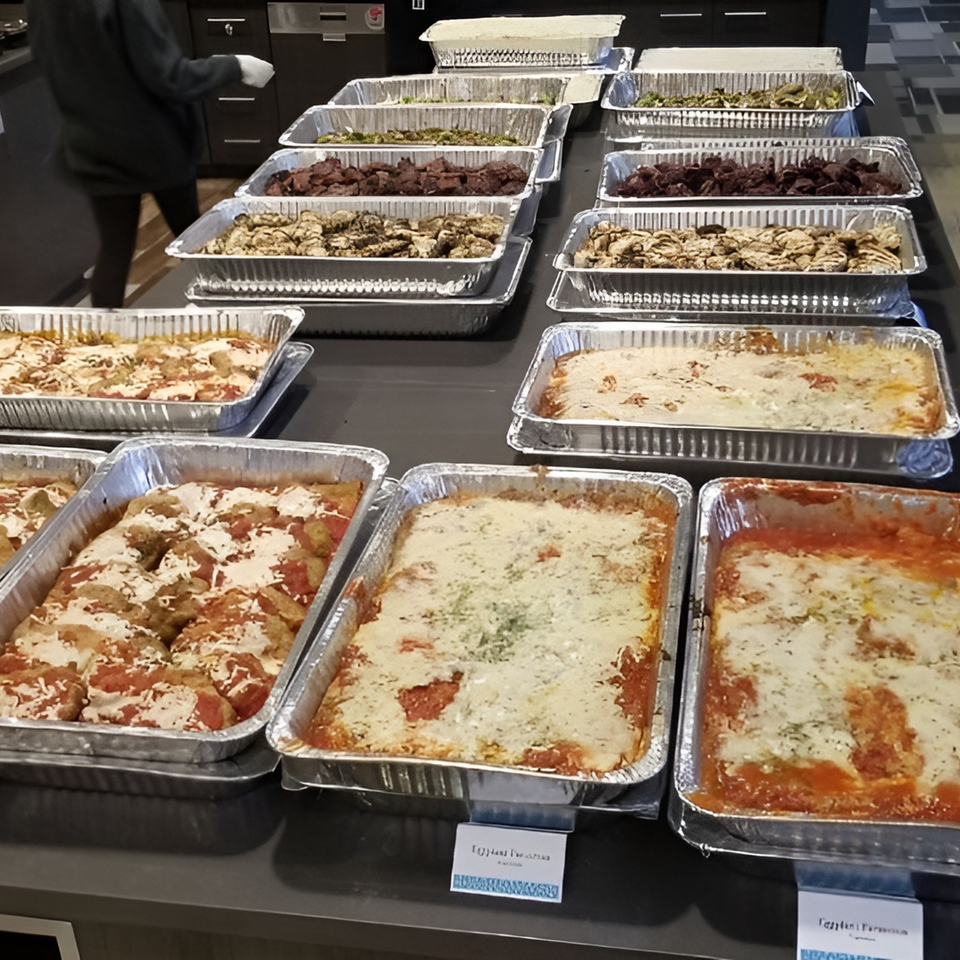 A buffet line of Michael G's Handcrafted Italian catering trays filled with various Italian dishes.